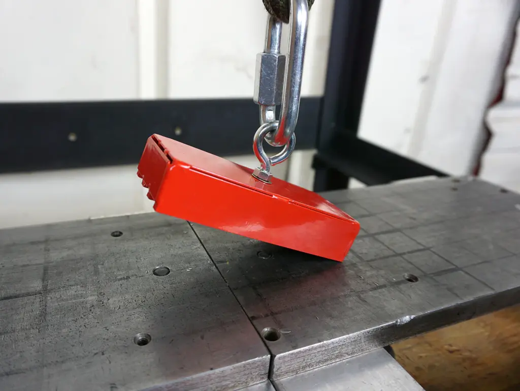 Magnet pull strength testing with tensile machine on steel surface.