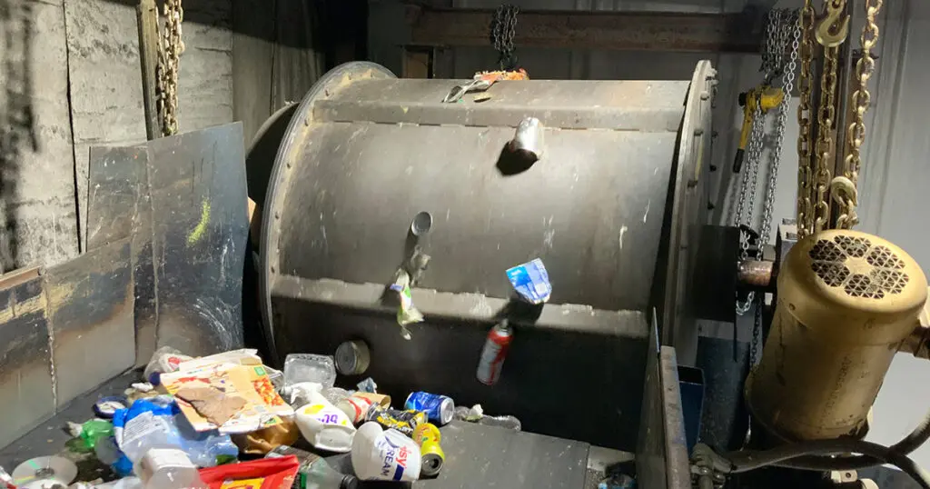Magnetic drum separator processing solid waste or construction debris in a recycling facility.